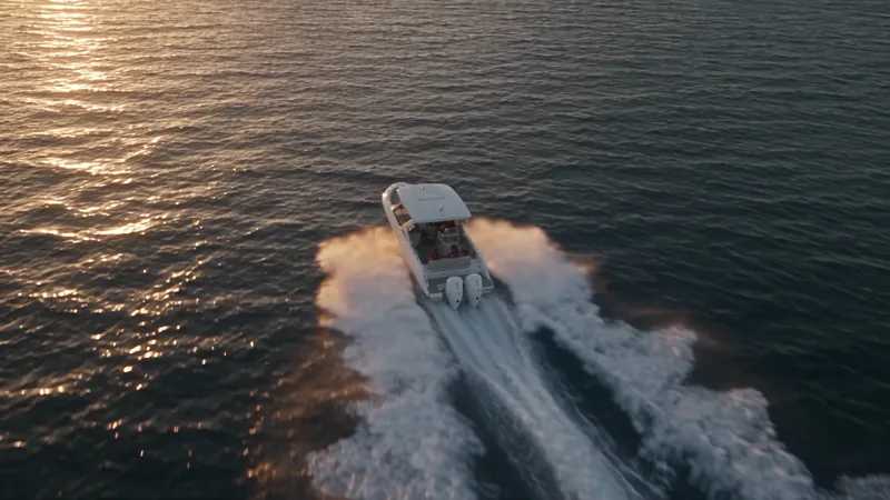 A Navion dual-console boat running toward the low sun across open water